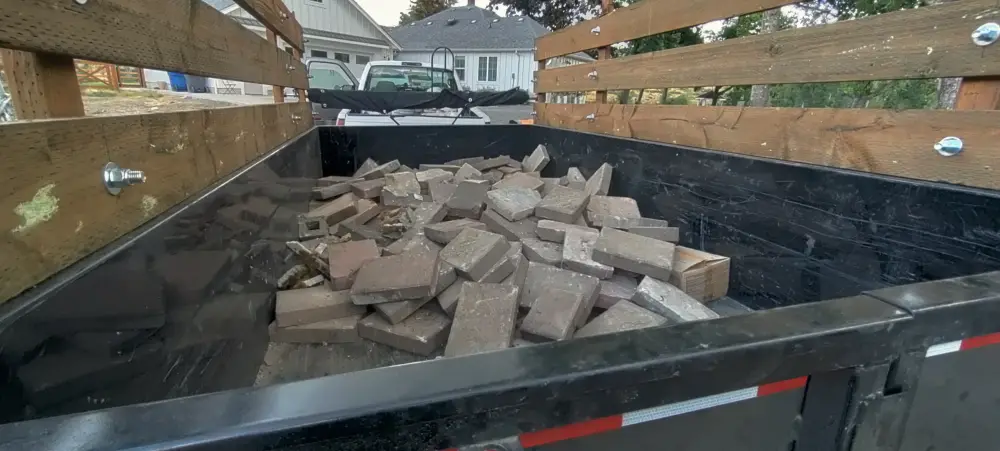 Dump trailer loaded with old brick pavers hauled from a patio removal in the Salem area