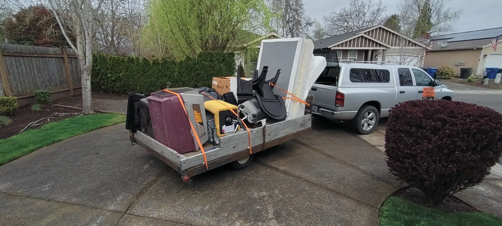 Ross Junk Removal trailer loaded with household debris on a residential street in West Salem